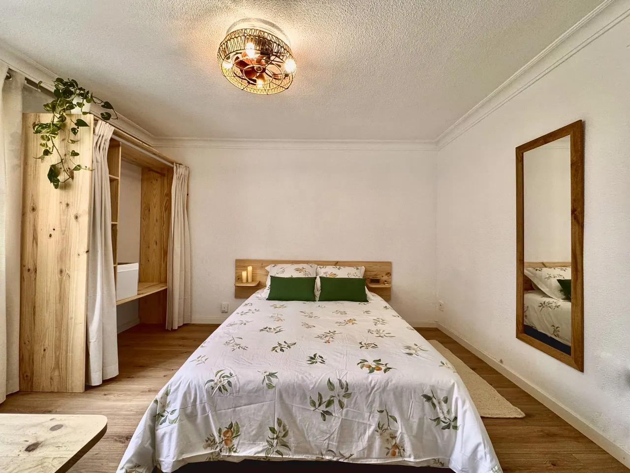 Habitación amplia con cama de matrimonio, espejo grande, armario abierto de madera y plantas