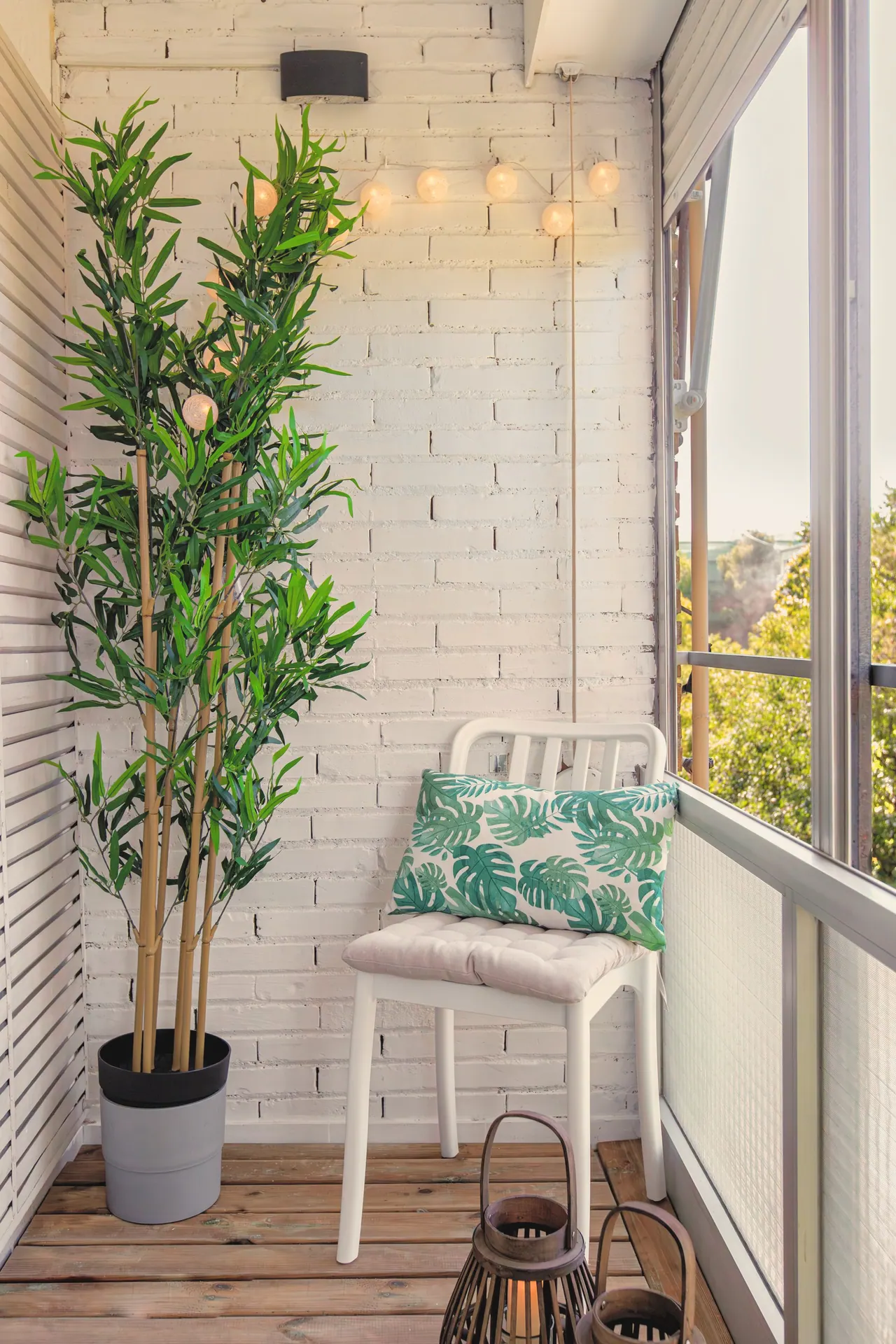 Terraza acristalada con silla blanca, cojín de hojas y planta grande (foto 5 de 7)
